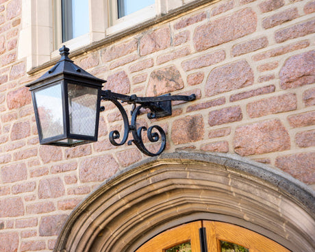 Custom wrought iron outdoor light fixture mounted on a stone wall