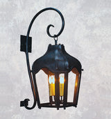 A decorative wrought iron sconce featuring an elegant curved arm and a lantern-like shade. Three candle-style bulbs illuminate the interior, casting a warm glow. The intricate design adds a touch of vintage charm, perfect for enhancing any indoor or outdoor space.