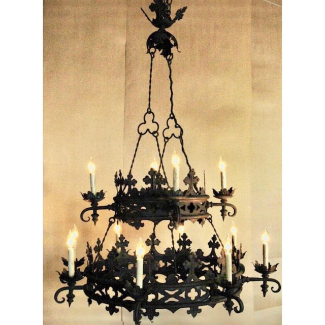 A stunning wrought iron chandelier featuring intricate scrollwork and decorative leaf accents, illuminated by flickering candle-style lights.