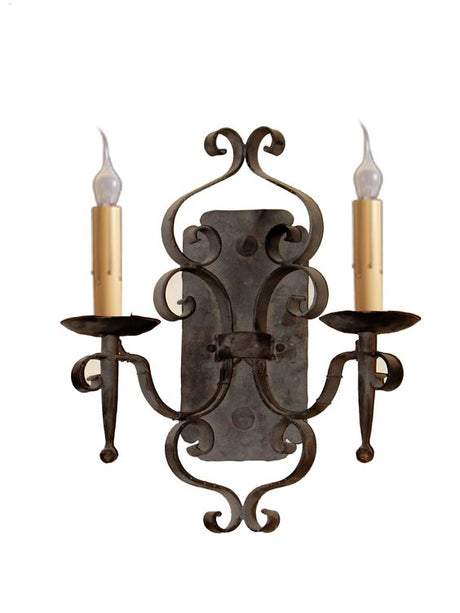 An elegant wrought iron wall sconce featuring intricate scrollwork and two candle-shaped lights. The design incorporates a dark finish with light-colored candle holders, creating a warm and inviting ambiance. Ideal for enhancing traditional or rustic decor.