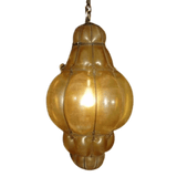 A beautifully crafted pendant light featuring a rounded, elongated shape with a warm, amber glow. The intricate wrought iron frame enhances its vintage charm, perfect for adding elegance to any space.