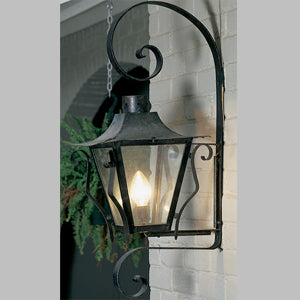 A decorative wall sconce featuring intricate wrought iron details and a classic glass lantern design, providing warm illumination to outdoor spaces.