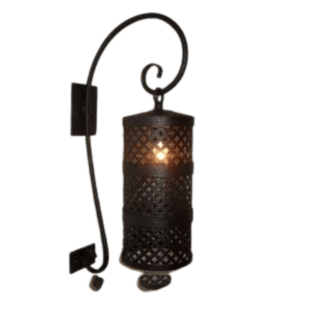 A decorative wall sconce featuring an intricately patterned cylindrical shade that houses a warm glowing light. The design includes a stylish curved arm and a textured black finish, adding elegance to any space.