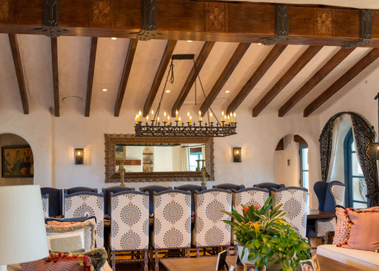 Spanish-style wrought iron chandelier and matching wall-mounted sconces featuring intricate scrollwork and candle-like lights, showcasing a rustic and traditional design.