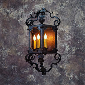 A decorative wrought iron sconce featuring an intricate design with ornate curls, holding three candle-style bulbs that emit a warm glow.