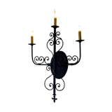 A beautifully crafted wrought iron sconce featuring three candle holders with elegant curves and scrollwork. The intricate design adds a touch of classic charm to any space, enhancing the ambiance with a warm glow.