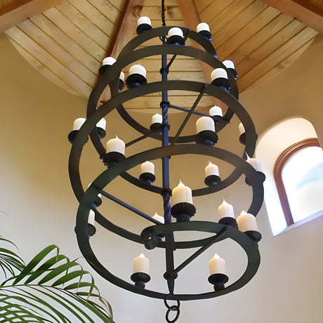 A striking wrought iron chandelier featuring multiple circular tiers adorned with candle-like lights, suspended from a wooden ceiling, adding elegance to the space.