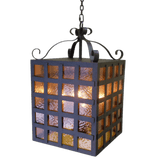 A hanging pendant light with a square design, featuring textured glass panels in warm hues. The wrought iron frame adds a rustic charm, accented by elegant scrollwork at the top, illuminating spaces with a cozy ambiance.