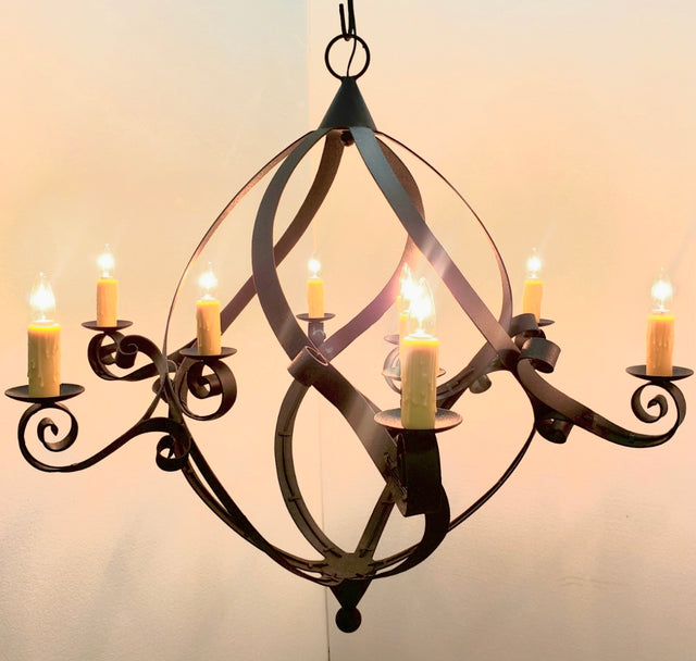 An elegant wrought iron chandelier featuring curved, swirling designs and eight candle-like lights, adding a warm ambiance to any space.