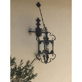 A decorative wrought iron wall sconce featuring intricate scrollwork and a candle-style light holder. The design includes ornate detailing, enhancing any space with a warm and inviting glow.