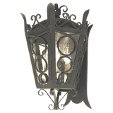 A decorative wrought iron sconce featuring an intricate design with circular cutouts and glass panels, showcasing soft, warm lighting inside.