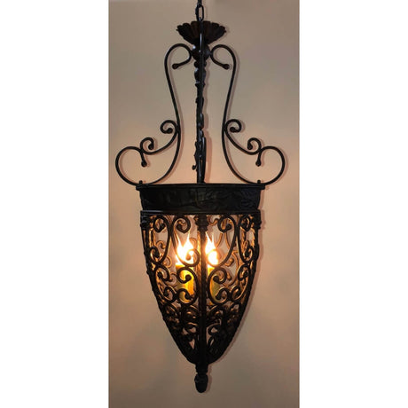 An ornate wrought iron pendant light with intricate scrollwork and an elegant design. The fixture features a decorative top and an open, lantern-like shape, showcasing two glowing bulbs inside, providing warm illumination.