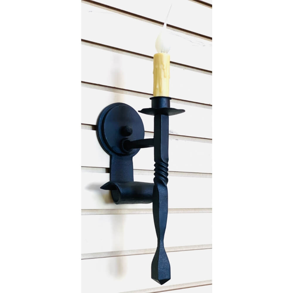 A black wrought iron wall sconce featuring a twisted arm and a candle holder, designed for a warm, inviting atmosphere. The fixture has a rounded base and a traditional look, enhancing any interior space.