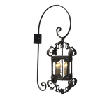 A decorative wall sconce featuring ornate wrought iron design with scrollwork details and a lantern-style housing. The fixture holds two candle-like bulbs, providing a warm glow. Ideal for enhancing traditional or rustic interiors.