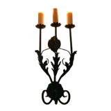 A beautifully crafted wrought iron sconce featuring three elegant candle holders. The design showcases intricate leaf patterns and a classic, elegant style that enhances any ambiance.