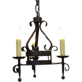 A decorative wrought iron chandelier featuring three candle-like bulbs, intricate scrollwork, and a robust, antique finish. Ideal for adding rustic elegance to any space.