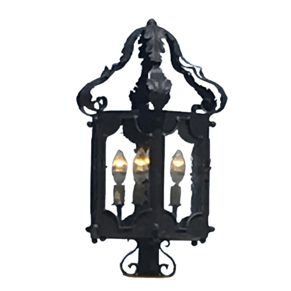 A detailed wrought iron sconce featuring intricate designs and three illuminated candle-style bulbs. The piece showcases elegant curves and ornate embellishments, perfect for enhancing any space with a warm ambiance.