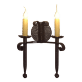 A decorative wrought iron sconce featuring two flickering candle-style bulbs, complemented by elegant curved accents and a central circular design, perfect for enhancing rustic interiors.