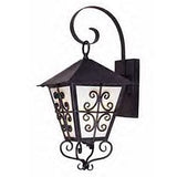 A charming wrought iron sconce featuring an intricate scroll design, set against a classic glass panel. The elegant top has a peaked roof and a decorative arm, perfect for enhancing outdoor spaces.