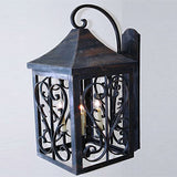 A decorative wrought iron wall sconce featuring intricate scrollwork, a peaked roof, and glowing candle-like lights, designed for elegant ambiance.