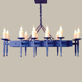 A wrought iron chandelier featuring eight candle holders with flame-like lights, elegantly suspended by a sturdy chain, showcasing intricate detailing and a rustic design.