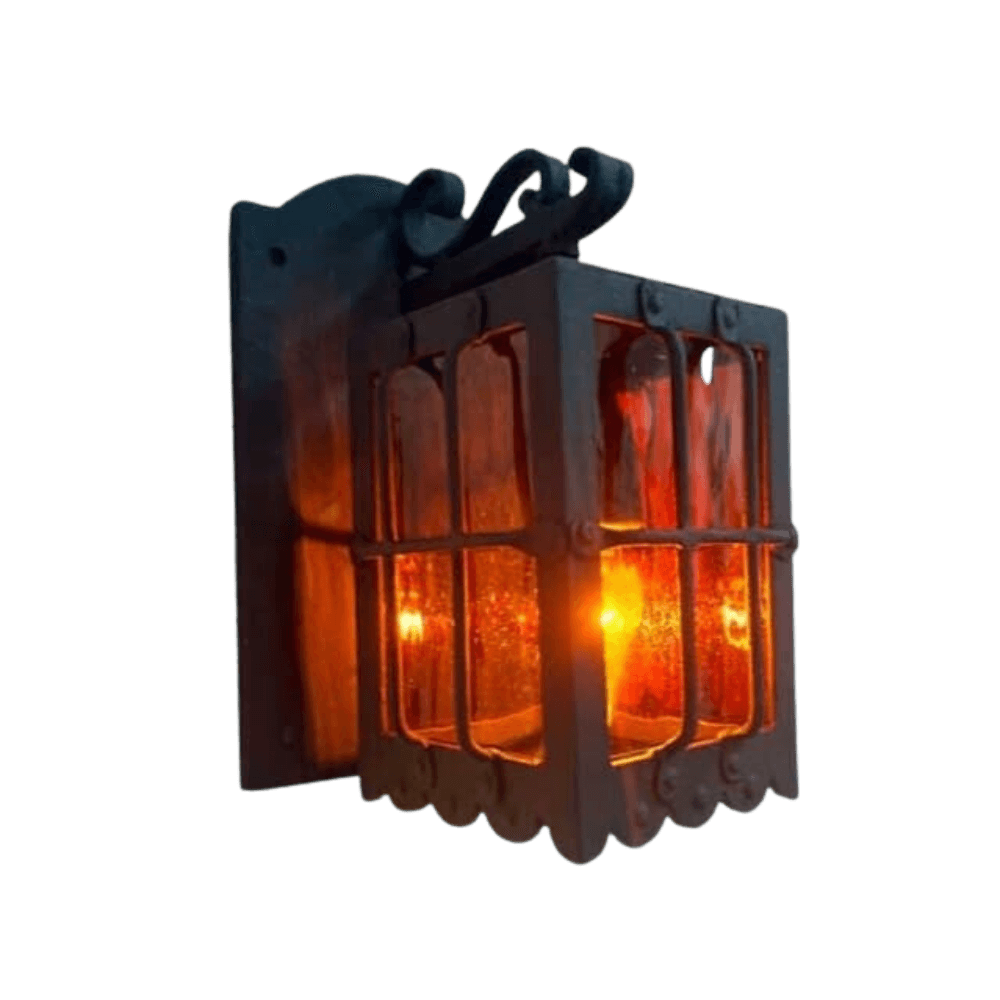 A rustic wrought iron sconce featuring a square design with ornate detailing, showcasing amber hues emanating from within. The fixture has a decorative edge and is suitable for enhancing any cozy or elegant space.