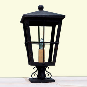 A decorative wrought iron sconce featuring a classic design, with a black finish, clear glass enclosure, and elegant scrollwork base.