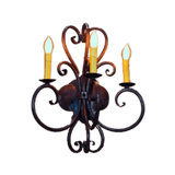 A decorative wall sconce featuring three candle-style bulbs atop ornate, swirling wrought iron arms. The design includes a central round fixture, showcasing elegant curves that enhance a classic ambiance.