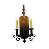 A hand-crafted wrought iron sconce featuring two candle-like lights and elegant scrollwork. The twisted center adds a touch of artistry and charm.