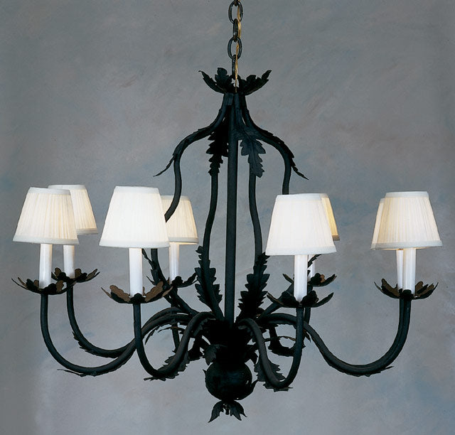 A beautifully crafted wrought iron chandelier featuring intricate scrolling and decorative leaves. It holds six soft white lamp shades, enhancing its elegant charm, ideal for adding warmth to any space.