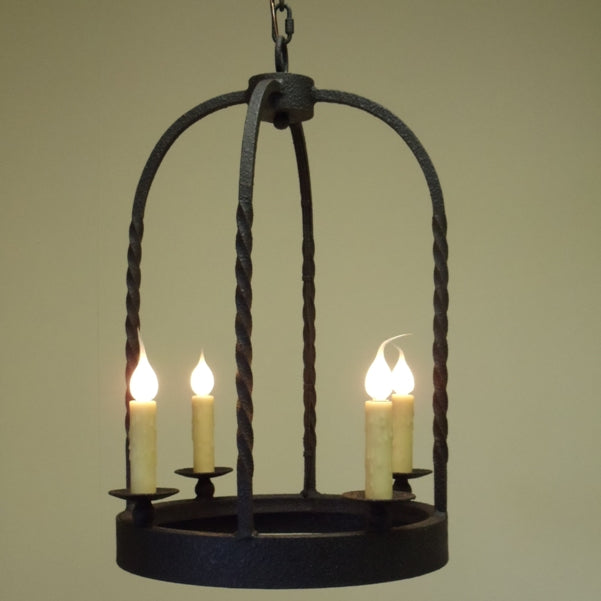 A rustic wrought iron chandelier featuring a rounded frame with twisted detailing. It holds three candle-like bulbs, emitting a warm glow, perfect for adding a touch of elegance to any space.