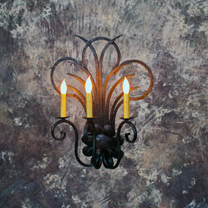 Elegant wrought iron sconce featuring ornate scrollwork and three candle-style lights. The design exudes classic charm, ideal for enhancing warm, inviting spaces.