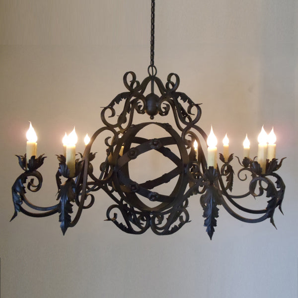 A beautifully crafted wrought iron chandelier featuring intricate, swirling designs and elegant floral accents. It is adorned with multiple candle-like lights, creating a warm and inviting atmosphere. The dark, rich finish complements both rustic and refined interiors, making it a standout piece for dining or living spaces.