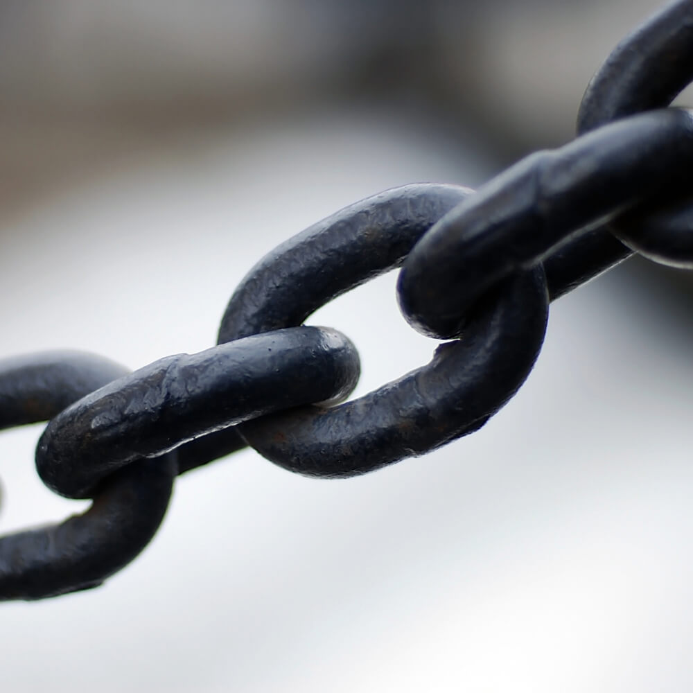 Dark brown chain links in focus on a blurred background