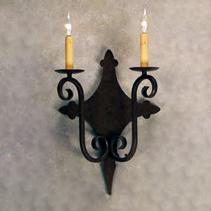 A decorative wrought iron sconce featuring two elegant candle-style lights with curved details and a diamond-shaped backplate, enhancing any indoor space with a touch of artistry.