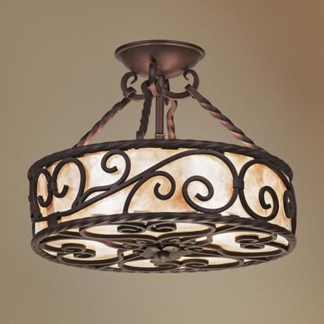 A stunning wrought iron chandelier featuring elegant, swirling scrollwork and a semi-translucent shade that emits a warm, inviting glow.