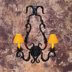 A decorative wrought iron sconce featuring ornate curves and flourishes, adorned with two amber lampshades. The intricate design adds a rustic charm to any space.