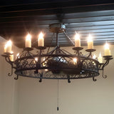 A large, ornate wrought iron chandelier featuring intricate scrollwork and candle-like lights, creating a warm and inviting atmosphere.