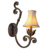 A decorative wall sconce featuring a curved wrought iron arm with intricate scrollwork, supporting a softly glowing fabric shade. The design combines elegance with a rustic charm, ideal for enhancing interior spaces.