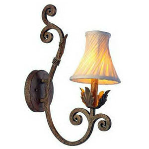 A decorative wall sconce featuring a curved wrought iron arm with intricate scrollwork, supporting a softly glowing fabric shade. The design combines elegance with a rustic charm, ideal for enhancing interior spaces.