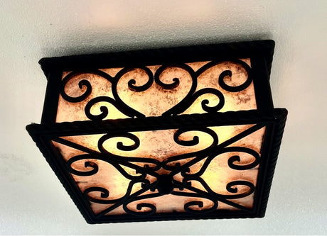 A decorative ceiling fixture featuring intricate wrought ironwork with swirling patterns. The warm amber glass panel softly diffuses light, creating an inviting ambiance.