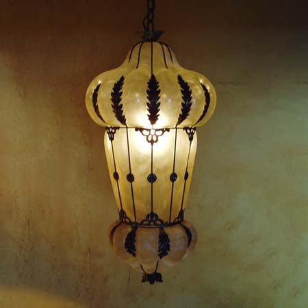 A beautiful pendant featuring elegant wrought iron accents and a soft, glowing amber shade. Its unique silhouette adds a touch of charm to any space.