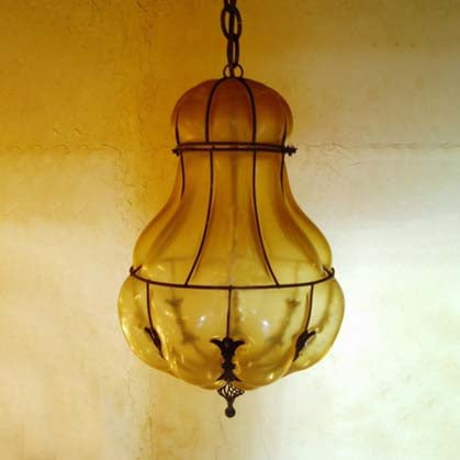 A stunning pendant light featuring a rounded, amber glass shade with elegant wrought iron accents. The design showcases a warm glow, perfect for adding style to any space.