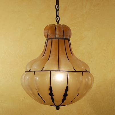 A beautifully crafted pendant light featuring a rounded, elegantly shaped glass shade in warm tones. The fixture is framed in intricate wrought iron, adding a touch of sophistication. Ideal for enhancing any space with a blend of classic and artistic style.