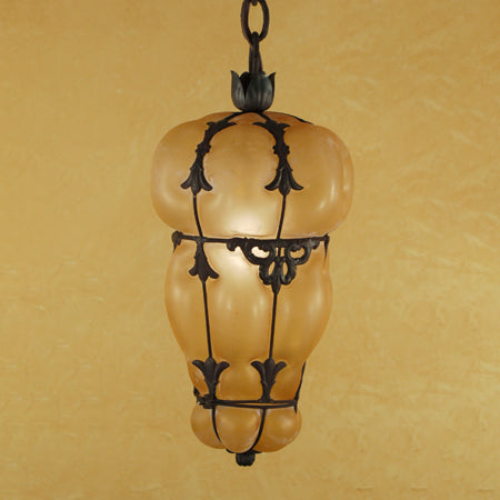 A decorative pendant light featuring a unique, curvy glass shade wrapped in an intricate wrought iron frame. The warm tones of the glass enhance the ambiance, while the detailed ironwork adds an elegant touch. Perfect for adding charm and character to any space.