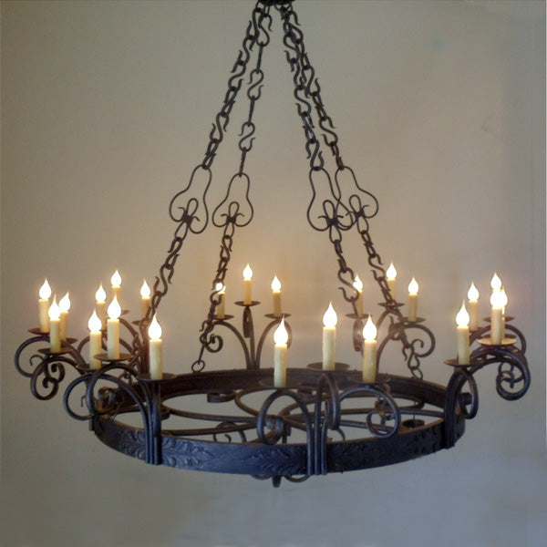 A beautifully crafted wrought iron chandelier featuring intricate scrollwork and elegant curves. It is adorned with multiple candle-like lights, creating a warm and inviting ambiance, perfect for dining or gathering spaces.