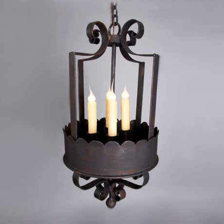 A decorative chandelier featuring elegant, curved wrought iron designs. It holds three candle-like lights surrounded by a scalloped base, creating a warm, inviting glow.