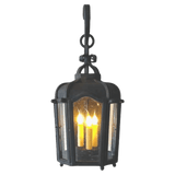 A beautifully crafted wrought iron pendant features a classic lantern shape with elegant curves. It showcases three candle-style lights within a glass enclosure, casting a warm glow. The fixture is suspended from a decorative hook, adding character and charm.