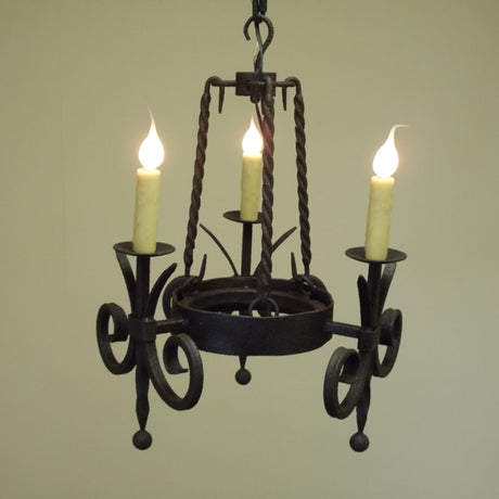 A black wrought iron chandelier featuring three candle-like lights, elegantly twisted details, and a charming, ornate design. Suitable for adding a touch of warmth and sophistication to any space.