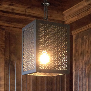 A stunning wrought iron pendant light featuring a geometric cut-out design, casting intricate shadows. Perfect for adding a warm ambiance to any room.